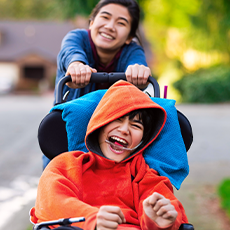 girl pushing boy with special needs in wheelchair