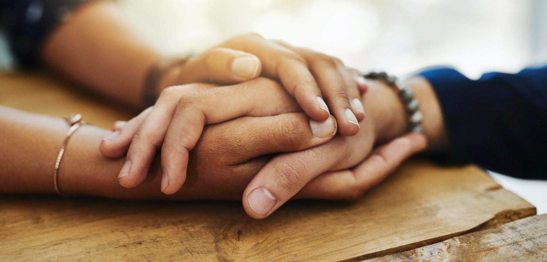 People holding hands on a tabletop