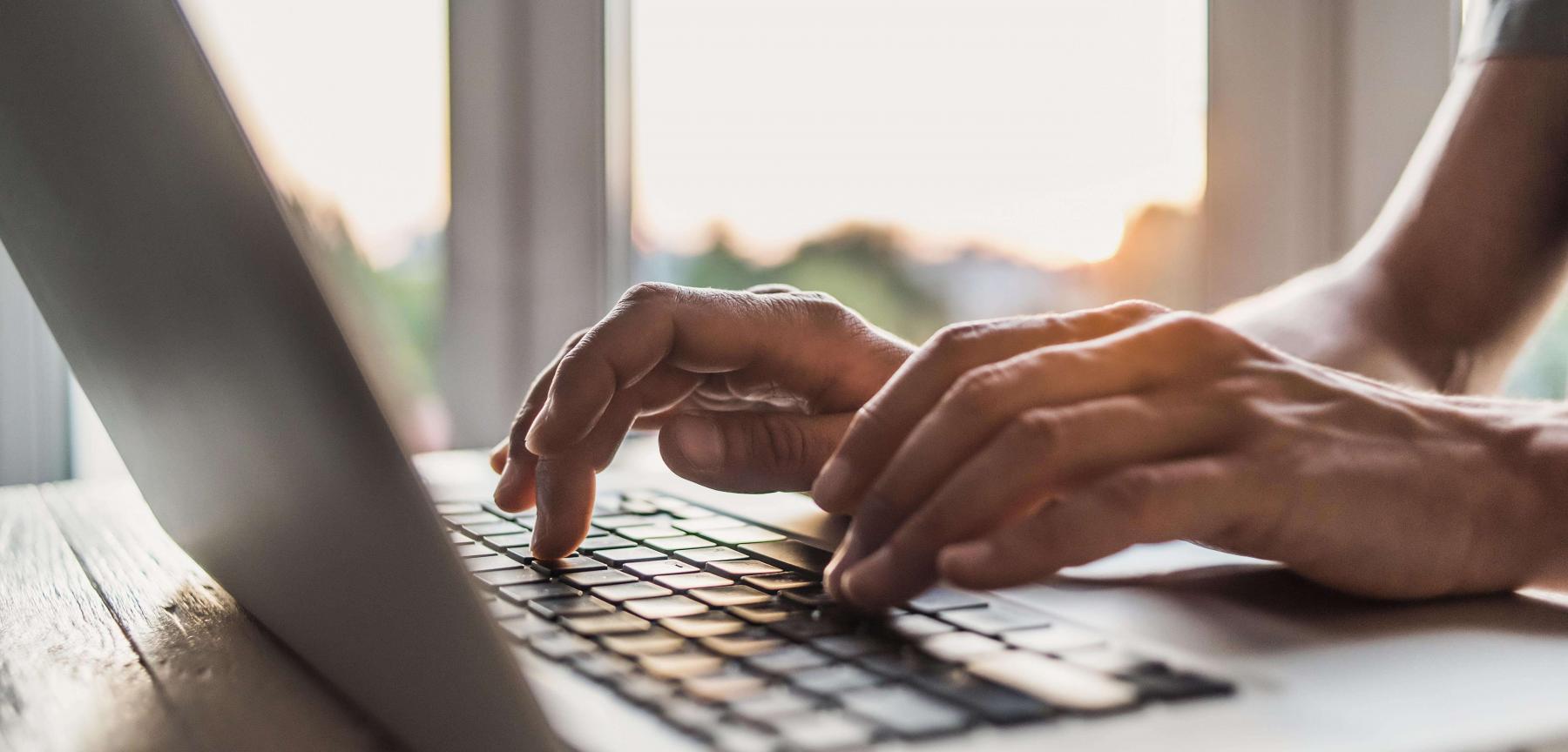 Hands typing on a laptop keyboard