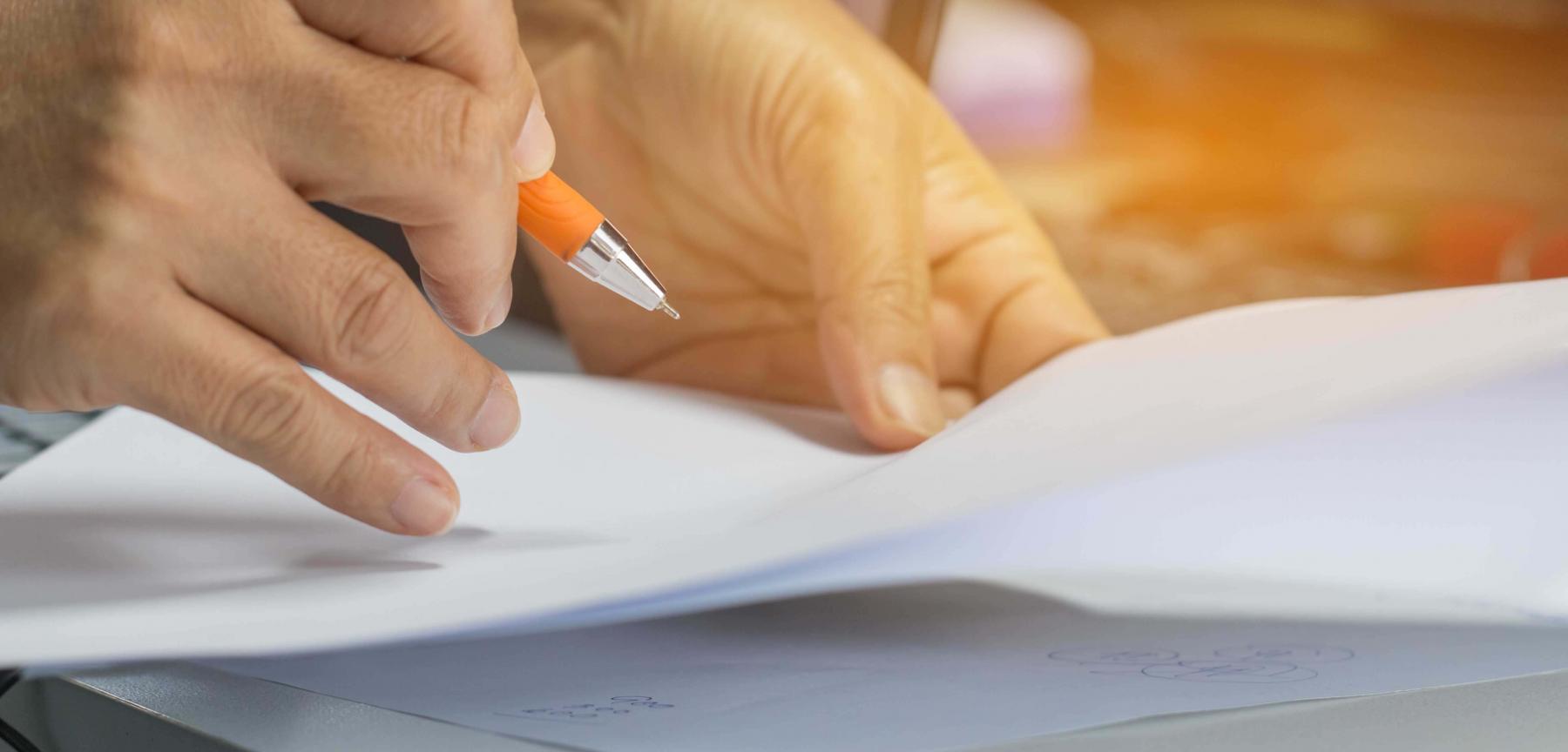 Hand holding a pen over paperwork